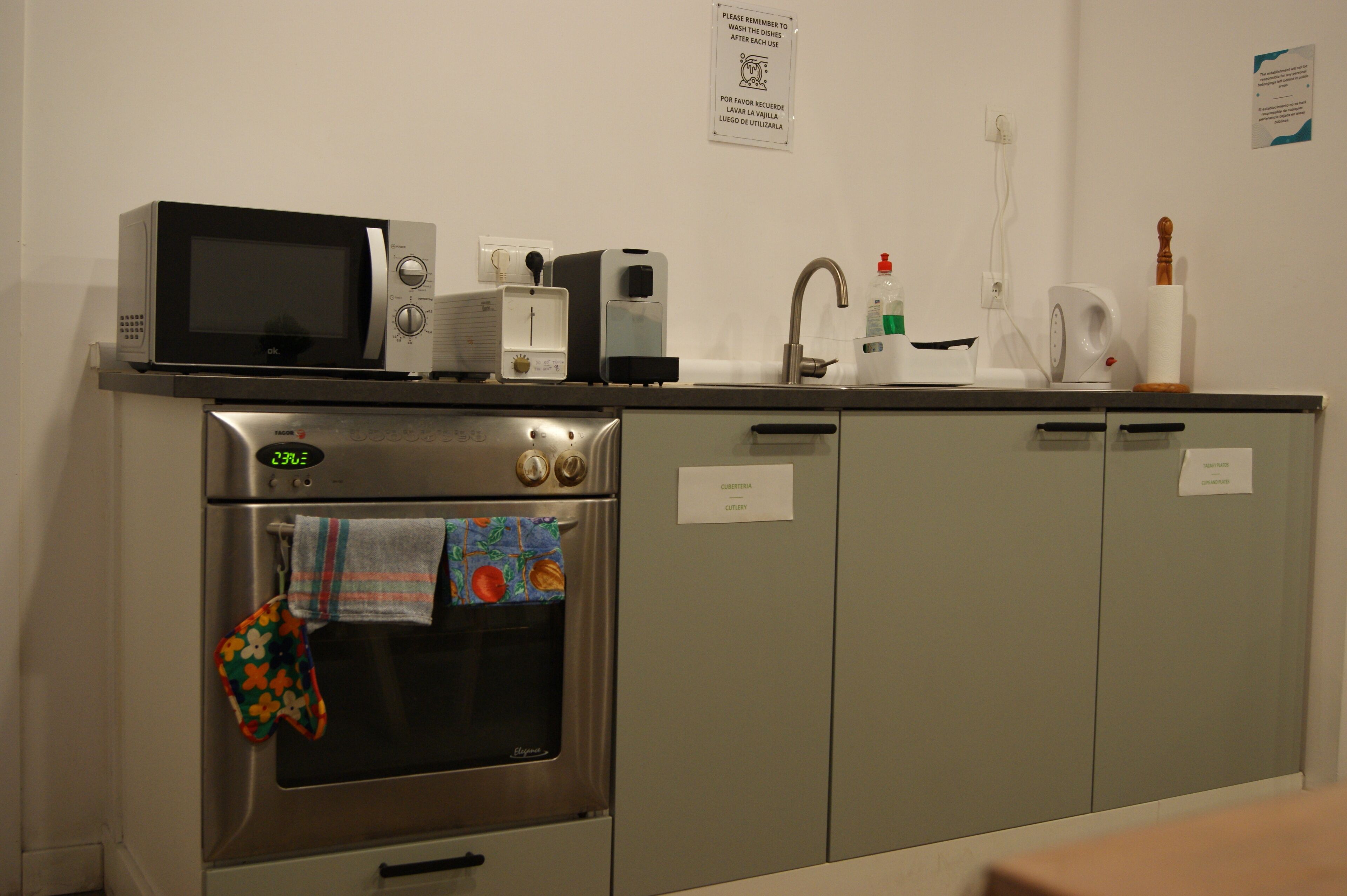 A kitchen with a microwave, toaster, and oven. There are cabinets and a sink with a faucet.