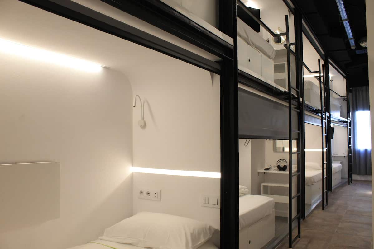 A hotel room with bunk beds, a bedside table, and a mirror.