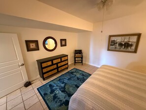 A bedroom with a bed, a dresser, a chair, a rug, and wall art. - Stella Maris • Walk to Cruz Bay • Pool • Generator Backup • Car Rental Available (Cruz Bay)