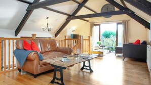 Ein Dachzimmer mit Holzbalkendecke, einem Ledersofa, einem Couchtisch und Blick ins Freie.