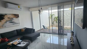 En moderne stue med en sort sofa, et glasbord og et billede på væggen.