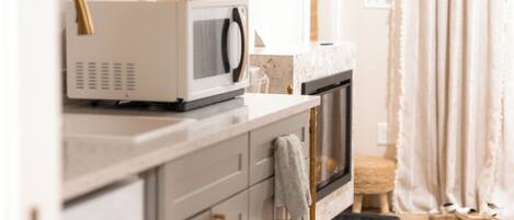 A kitchen with a microwave, oven, and a wooden floor.