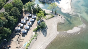 An aerial view of a beachside RV park with multiple RVs parked along the shore, surrounded by trees and a clear view of the adjacent water body. - Hideaway Bay Resort (Silver Creek)
