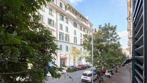 Une vue de rue avec des voitures garées et un immeuble doté de nombreuses fenêtres et de balcons.