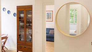 Une pièce avec un meuble en bois, un miroir rond et un canapé bleu.