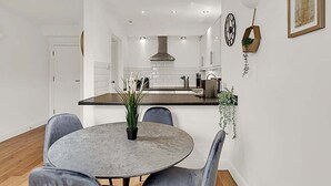 A modern kitchen with white cabinets, a black countertop, and a round dining table with chairs. - Contemporary Oasis in Paddington III (London)