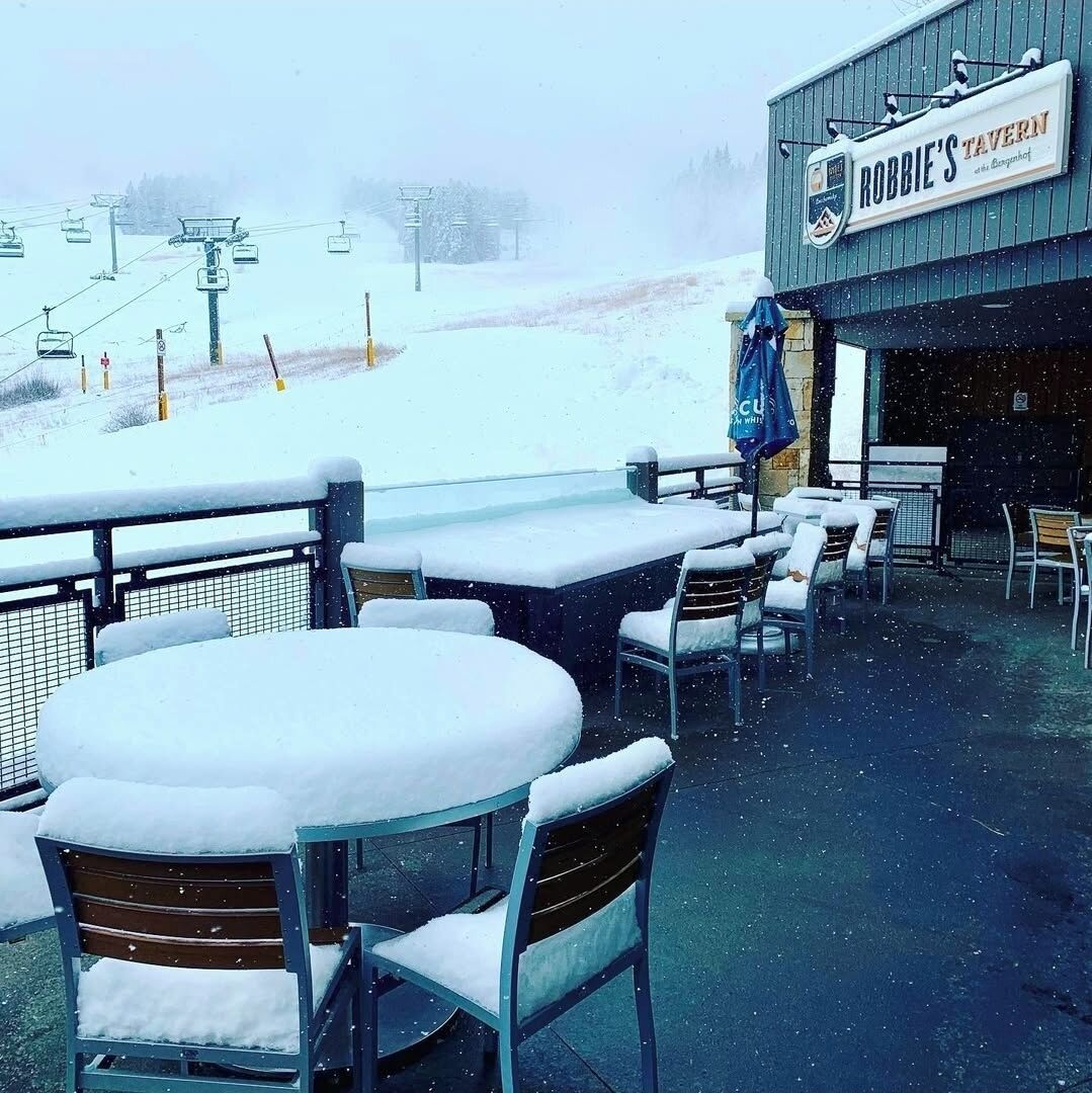 Un área de estar al aire libre con mesas y sillas cubiertas de nieve en Robbie's Tavern.