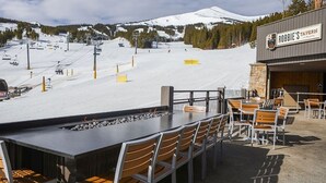 Un restaurante con terraza al aire libre y vistas a una montaña nevada.
