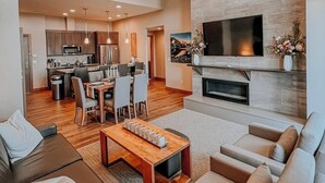 Una sala de estar moderna con chimenea, un comedor y una cocina al fondo.