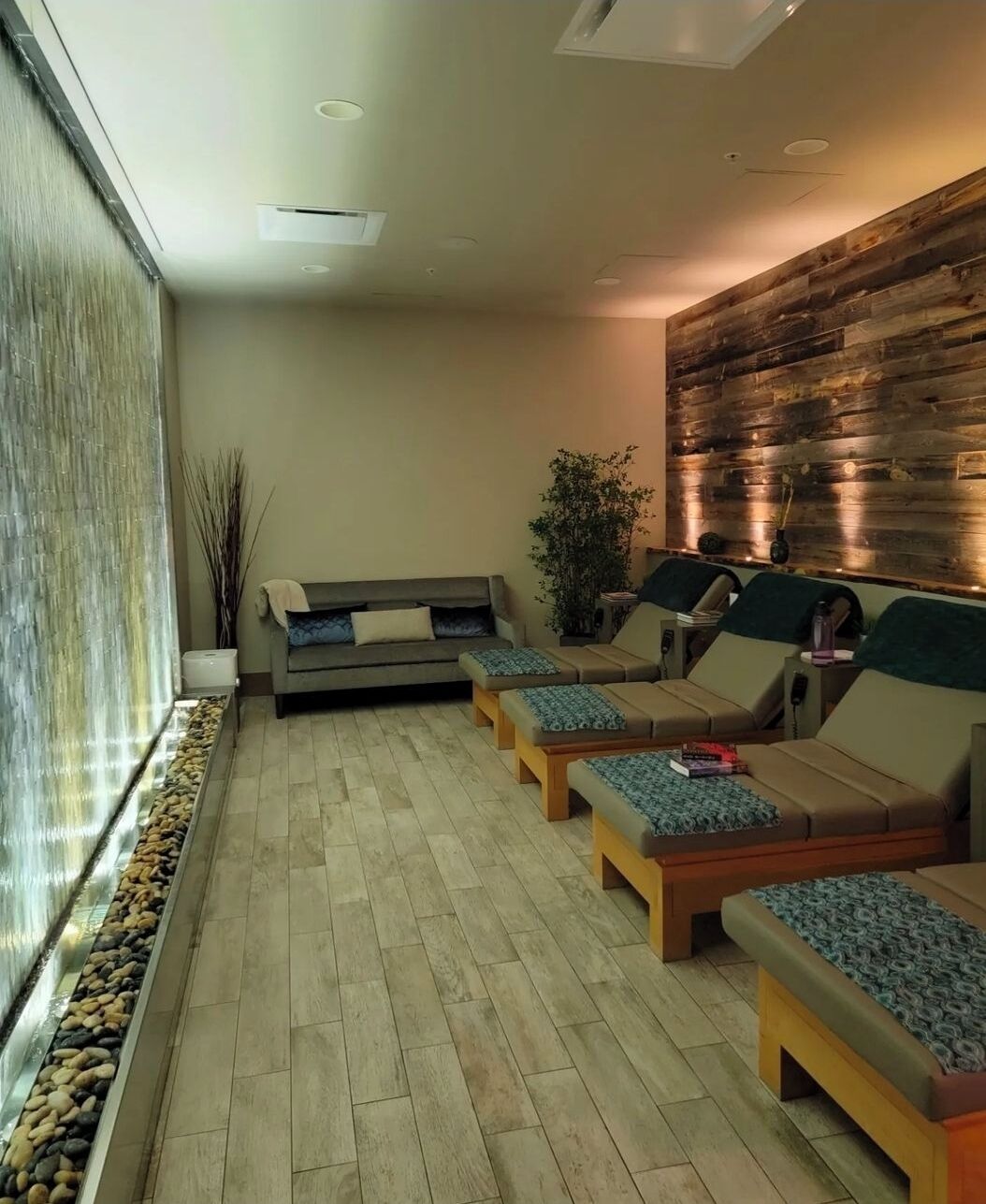 Ein Wellnessbereich mit Holzwand, einer Couch und Liegesesseln.
