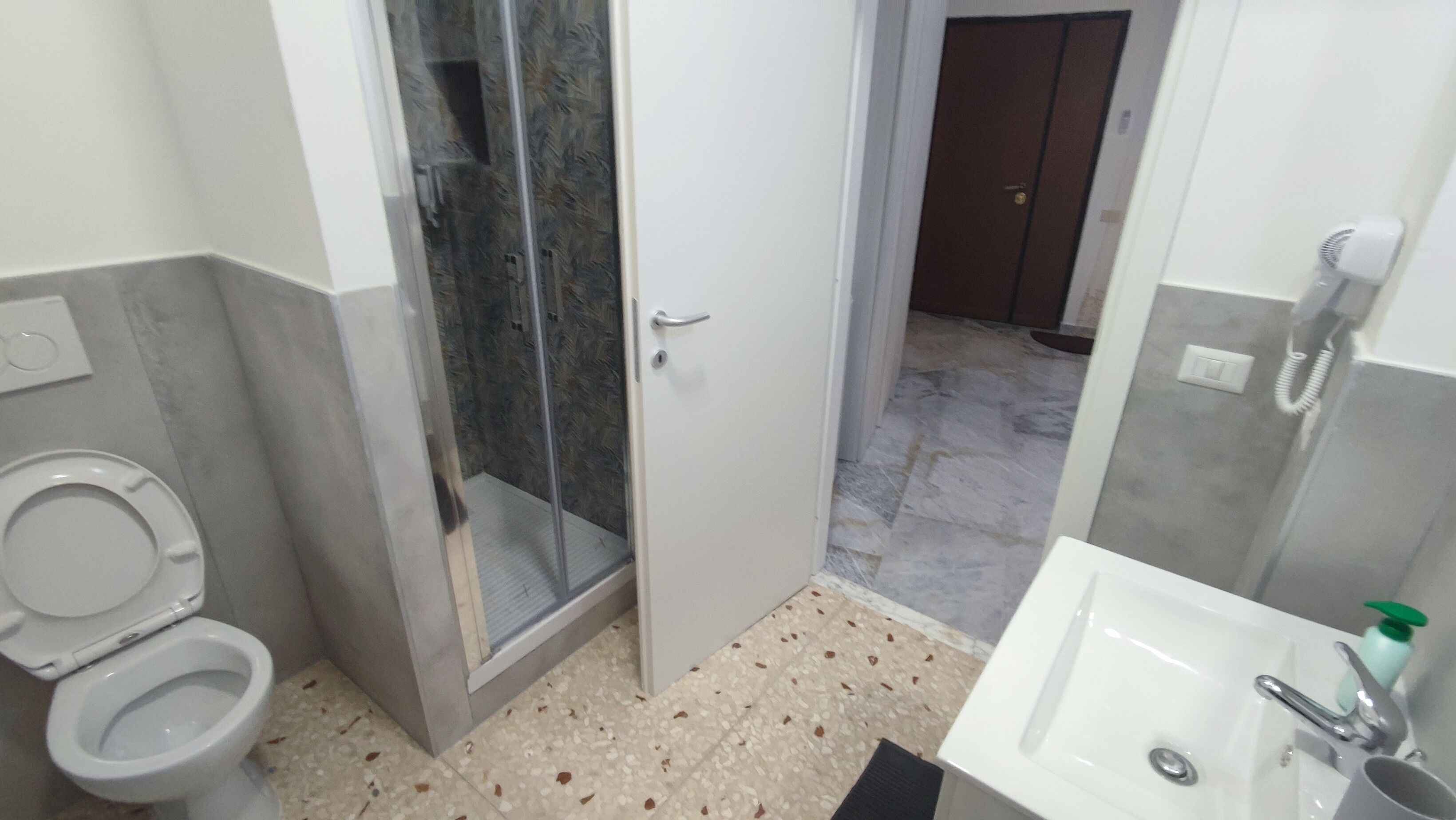 A bathroom with a toilet, a shower enclosure, and a sink.
