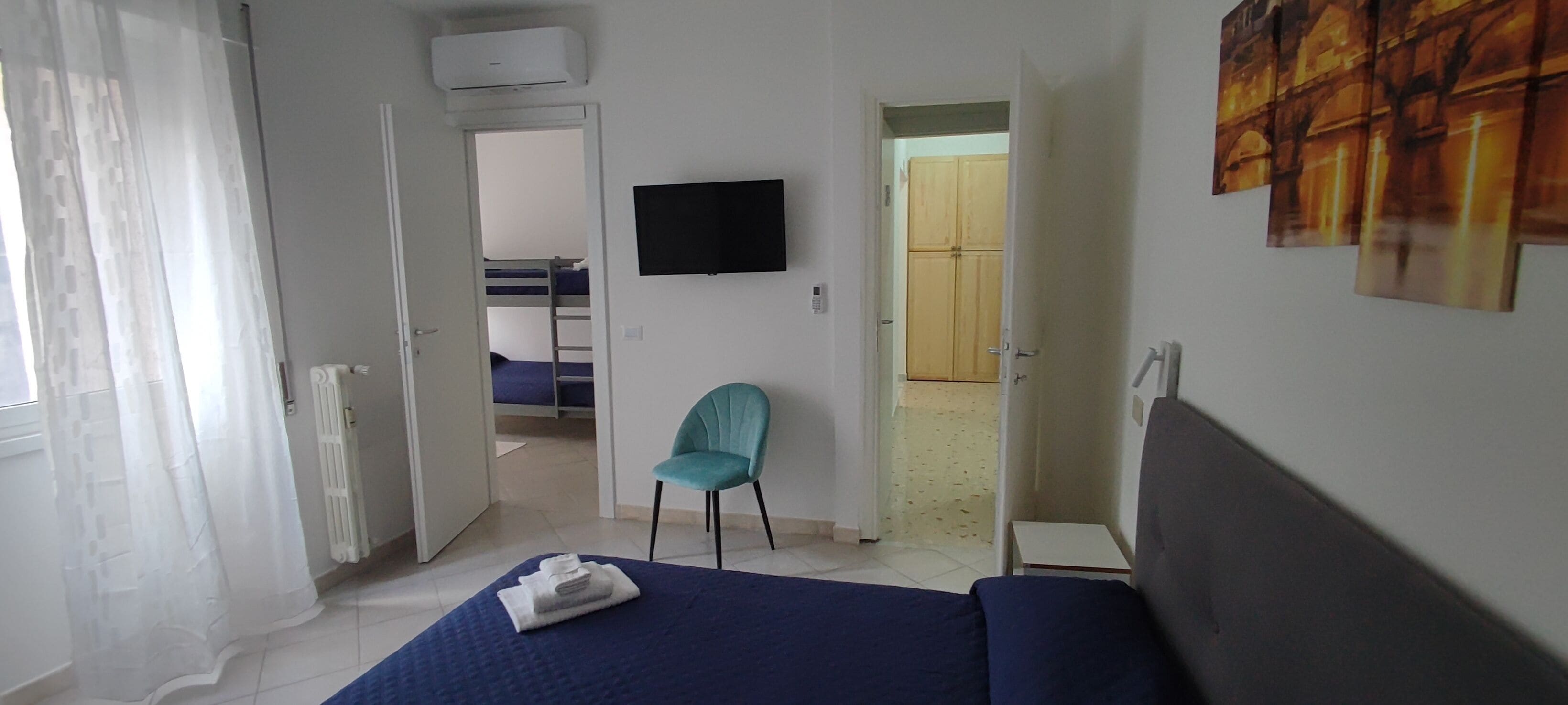 Ein Hotelzimmer mit Bett, Sessel, Flachbildfernseher und Kleiderschrank.