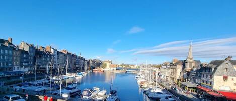 A marina with boats docked, a church spire, and buildings along the waterfront.