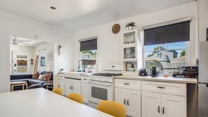 A modern kitchen with white cabinets, a gas stove, and a dining area with a table and chairs.