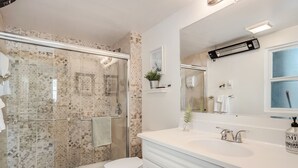 A modern bathroom with a glass-enclosed shower, a white toilet, and a vanity with a mirror and sink.