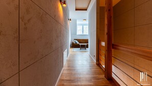 Un pasillo con piso de madera, un sofá marrón y una ventana al fondo.