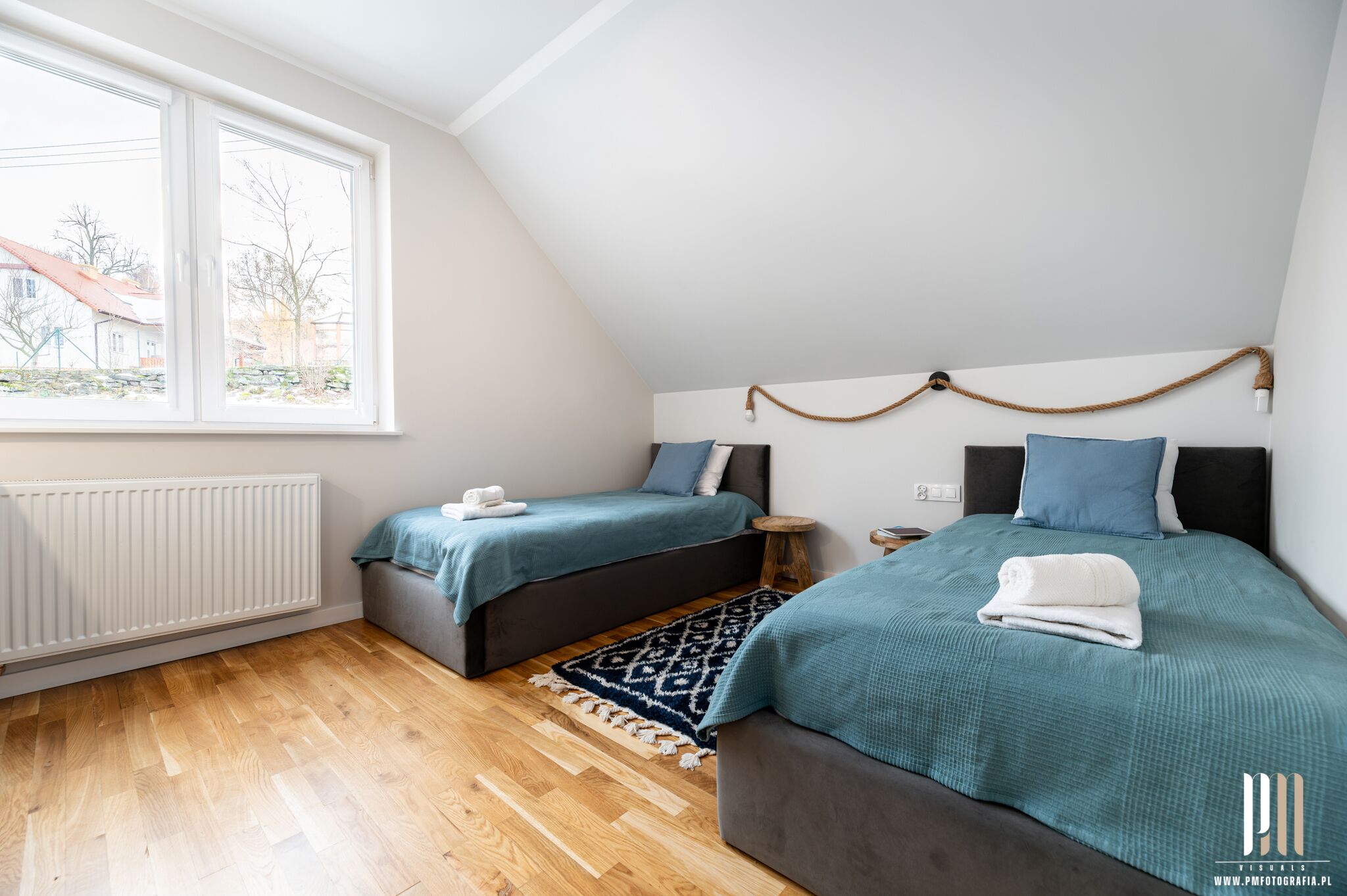 Ein Schlafzimmer mit zwei Betten, einem Fenster, einer Heizung und einem gemusterten Teppich.