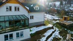 Una casa moderna con un amplio balcón de vidrio, un sendero de piedra y una estructura de madera en el jardín.