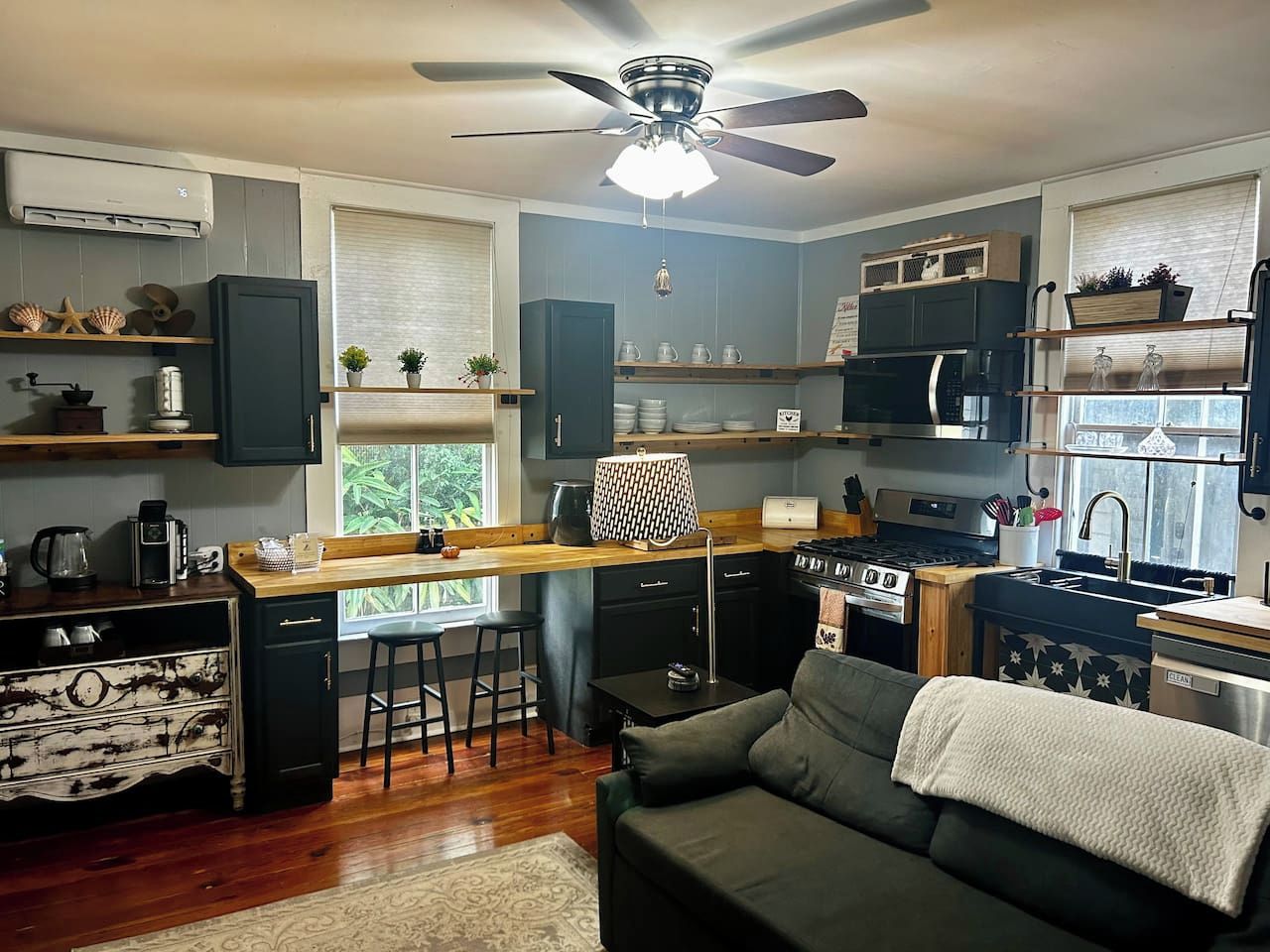 A compact kitchen with a central island, a ceiling fan, and a view of the outdoors through a window.