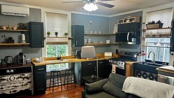 A compact kitchen with a central island, a ceiling fan, and a view of the outdoors through a window.