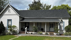 A single-story house with a front porch, a small front yard, and a gravel pathway leading to the entrance.