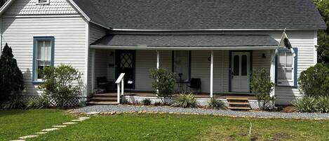 A single-story house with a front porch, a small front yard, and a gravel pathway leading to the entrance.