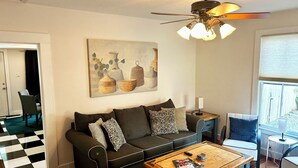 Una sala de estar con sofá, mesa de centro y una obra de arte en la pared.