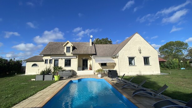 Ein zweistöckiges Haus mit Swimmingpool, einer überdachten Terrasse und einem gepflegten Rasen.