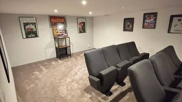Una habitación con piso alfombrado, un sofá seccional y cuadros enmarcados en las paredes.
