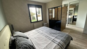 Ein modernes Schlafzimmer mit einem großen Bett, einem Fenster und Balkonblick.