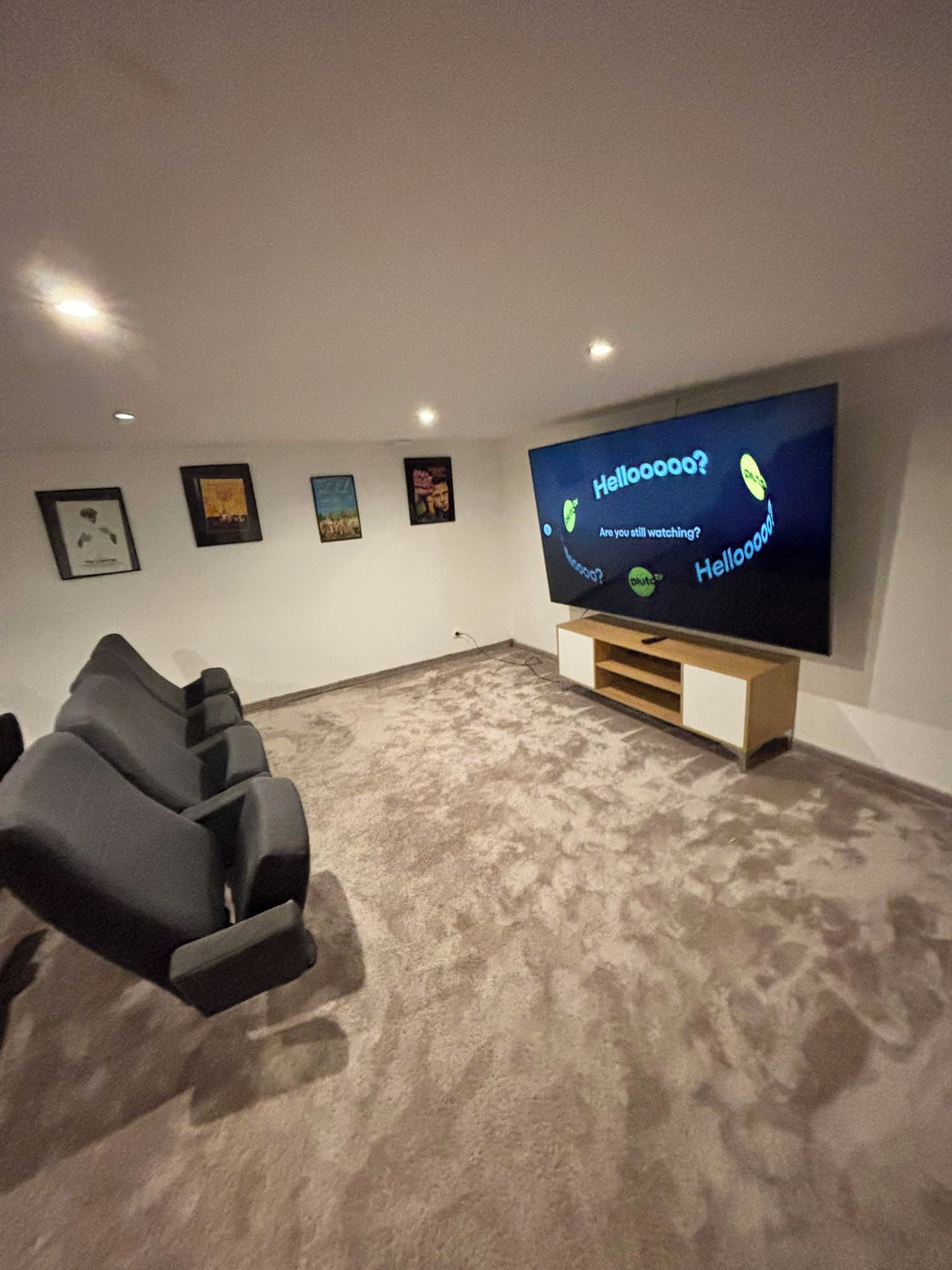Un cine en casa con un televisor de pantalla plana grande, un sillón reclinable y cuadros en la pared.