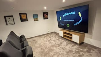Un cine en casa con un televisor de pantalla plana grande, un sillón reclinable y cuadros en la pared.