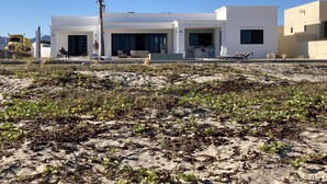 A modern beachside building with large windows, a patio area, and a view of the ocean.