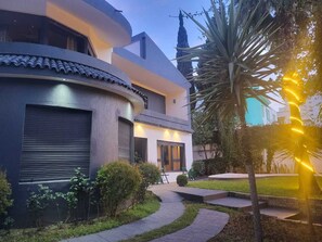 A modern house with a curved facade, a covered patio, and a well-maintained garden. - VILLA ADAM (Tangier)