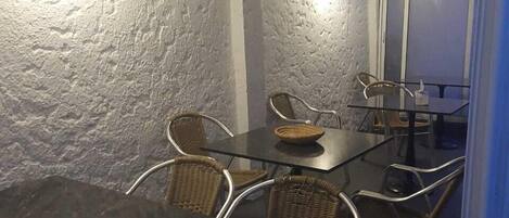 A dining area with a table and chairs, a hanging light fixture, and a view of the outside through a window.