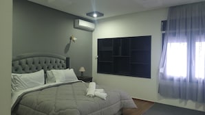 A bedroom with a tufted headboard, a large window with a view, an air conditioning unit, and a bedside table with a lamp. - VILLA ADAM (Tangier)