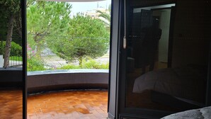 A room with a bed, a sliding glass door leading to a balcony, and a view of greenery outside. - VILLA ADAM (Tangier)