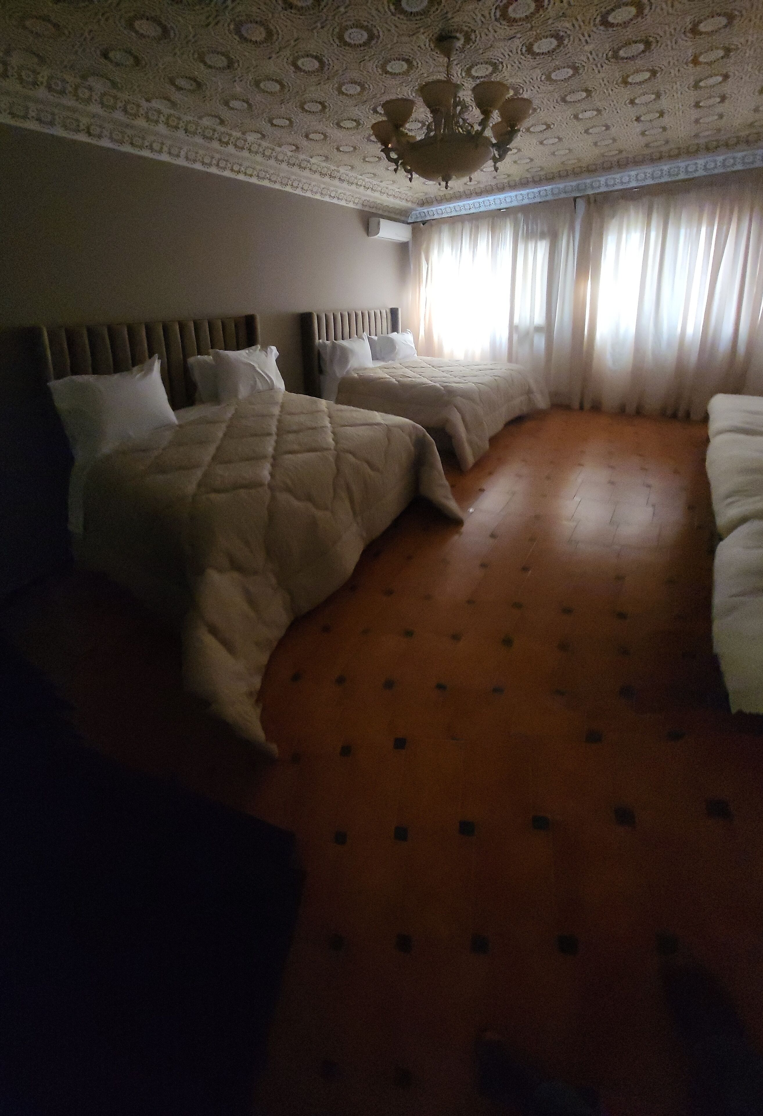 Habitación de hotel con dos camas, techo estampado y suelo de madera.