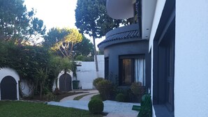 A courtyard with a paved path, a bench, and a small garden area with a palm tree. - VILLA ADAM (Tangier)