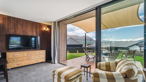 Ein modernes Wohnzimmer mit Fernseher, Holzschrank und gestreifter Couch.
