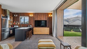 Eine moderne Küche mit einer zentralen Kochinsel, integrierten Geräten und einem großen Fenster mit Blick auf eine gebirgige Landschaft.