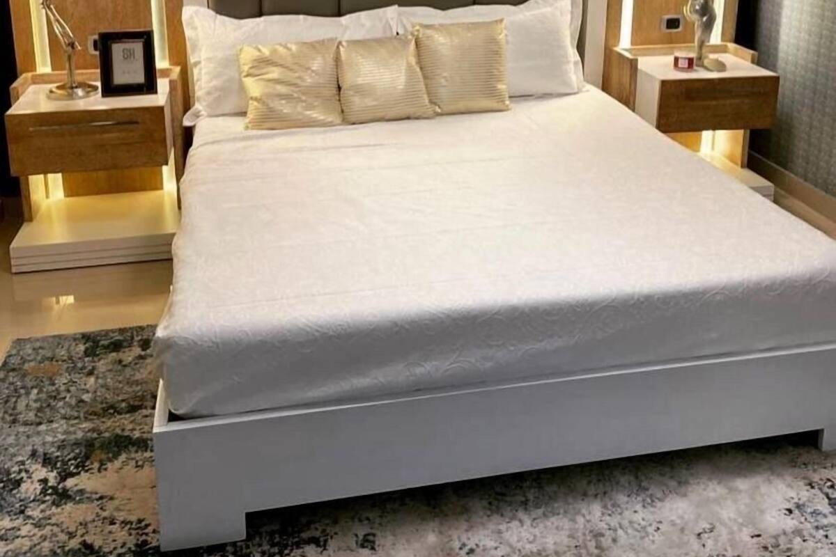 A modern bedroom with a large bed, two bedside tables with lamps, and a ceiling light fixture.
