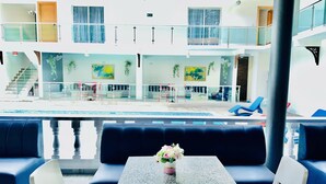 A poolside area with seating and a table, a staircase, and a view of the pool. - El Paso Hotel (Laguna Salada)
