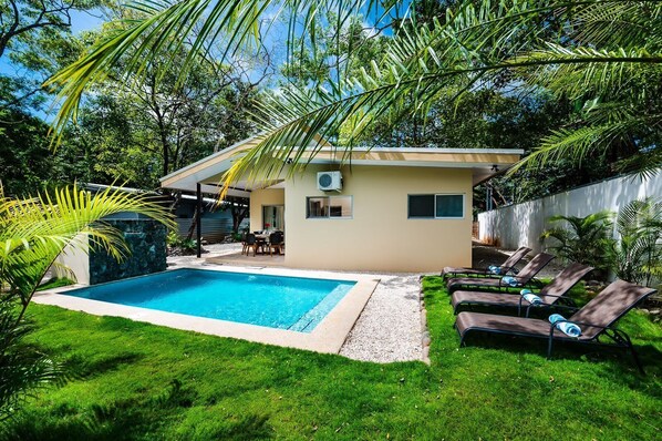 A backyard with a swimming pool, a covered patio, and lounge chairs. - Cozy 3bd private house & pool & walk to beach - Pets welcome! (Playa Negra)
