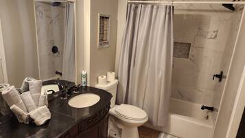 Tina con regadera, toallas, jabón, shampoo