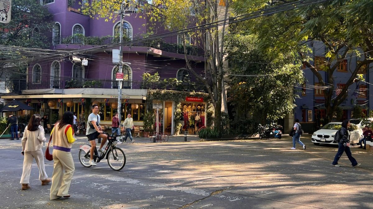 Une scène de rue avec des piétons, un cycliste et une voiture garée.
