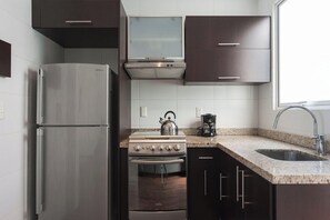 Een keuken met een roestvrijstalen koelkast, een fornuis en een spoelbak.