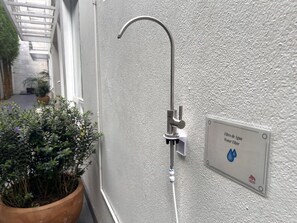 A water filter sign on a wall, a metal shower head, and a potted plant.