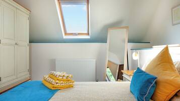 Une chambre à coucher avec un lit, une fenêtre, un radiateur, une armoire et un miroir.