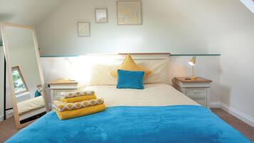A bedroom with a bed, two bedside tables, a nightstand, a mirror, and three framed pictures on the wall.